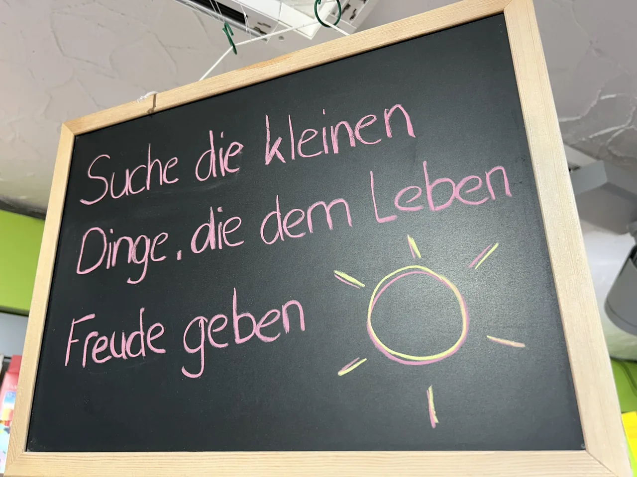 Handgeschriebene Tafel mit dem Spruch Suche die kleinen Dinge, die dem Leben Freude geben