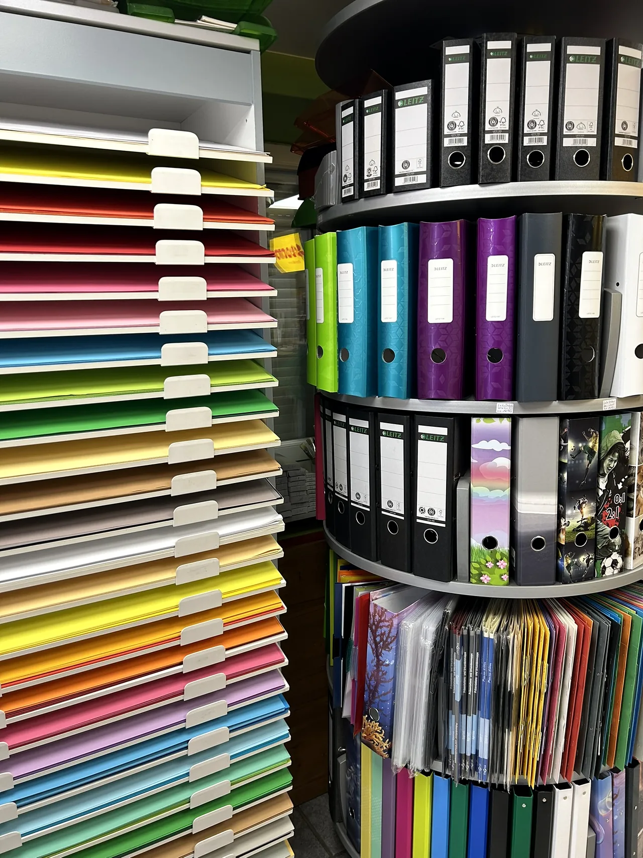 Farbiges Papier neben einem Ständer mit Ordnern